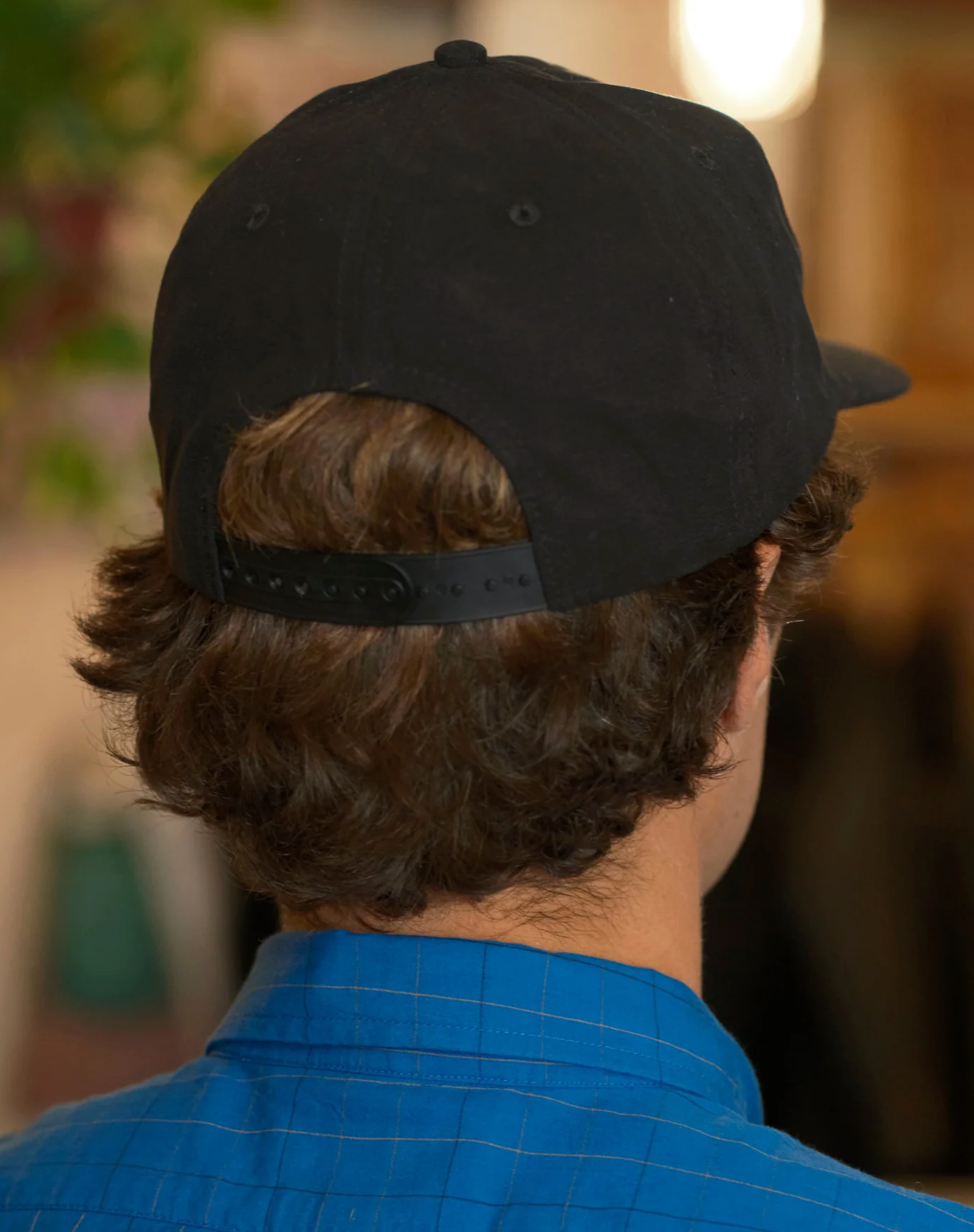 Person wearing a black cap and blue shirt with a blurred background