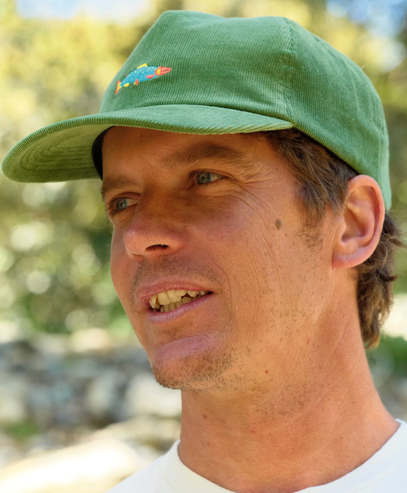 Man wearing a green cap with a colorful design outdoors