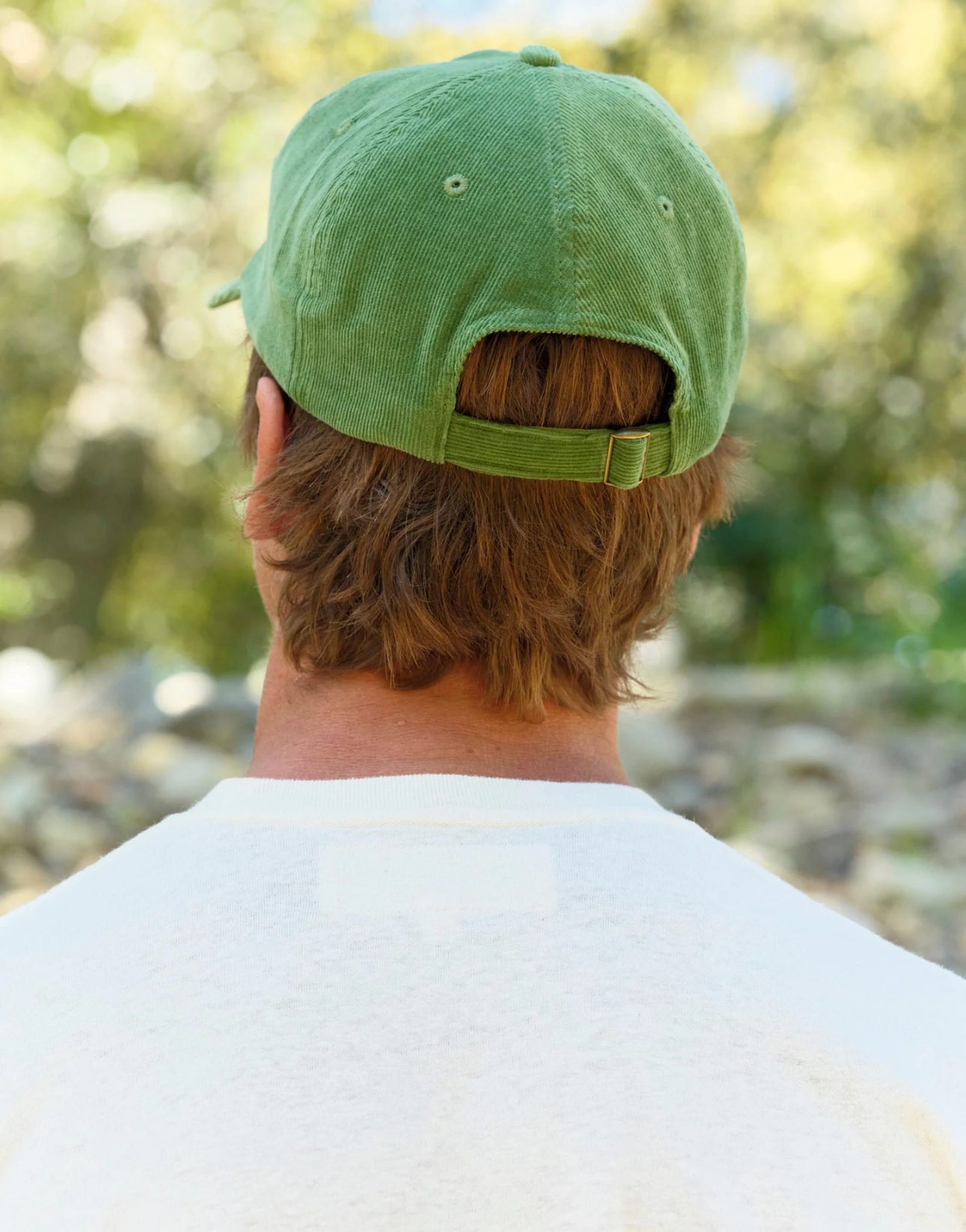 Person wearing a green cap with a blurred natural background