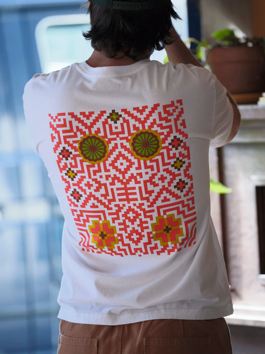 Person wearing a white t-shirt with a colorful geometric pattern on the back, standing indoors.