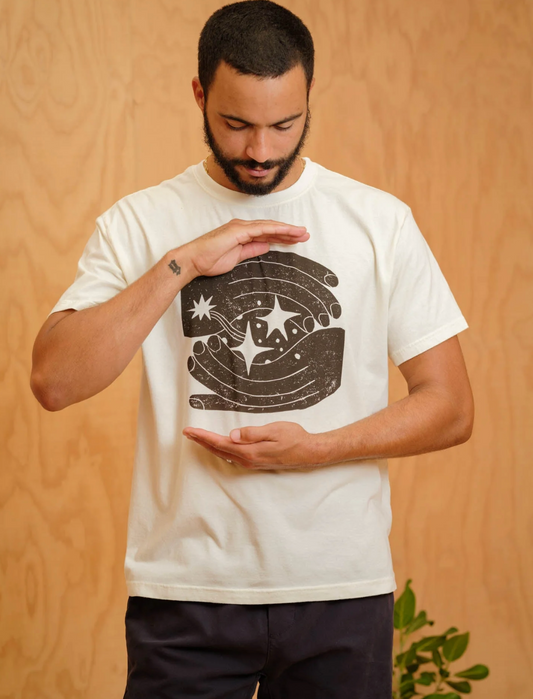 Man wearing a white t-shirt with a graphic design on a wooden background