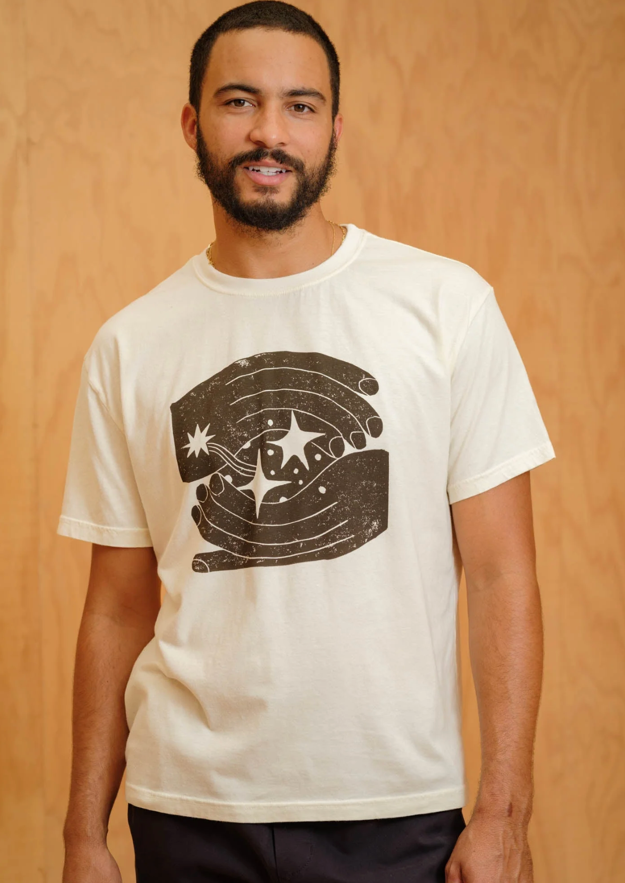 Man wearing a white t-shirt with a graphic design on a wooden background