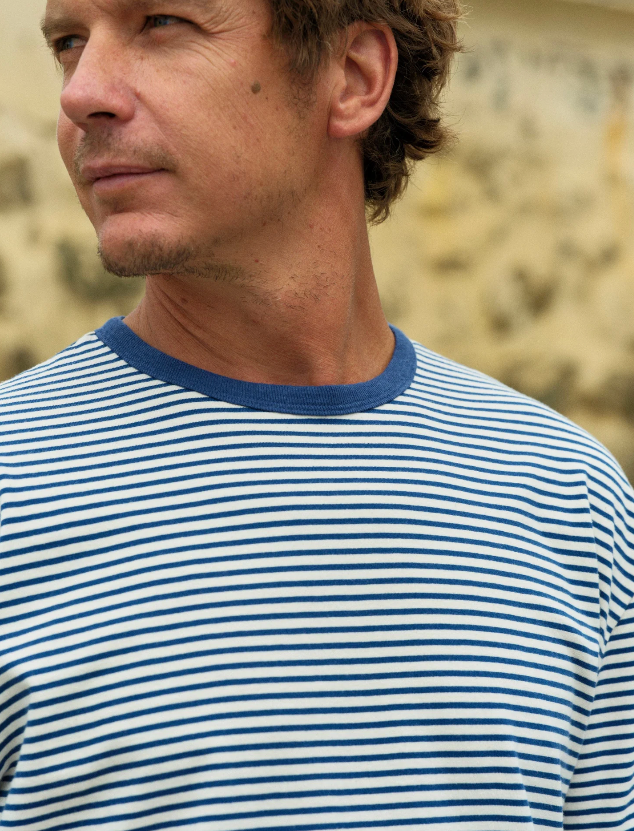 Man wearing a blue and white striped shirt against a blurred natural background