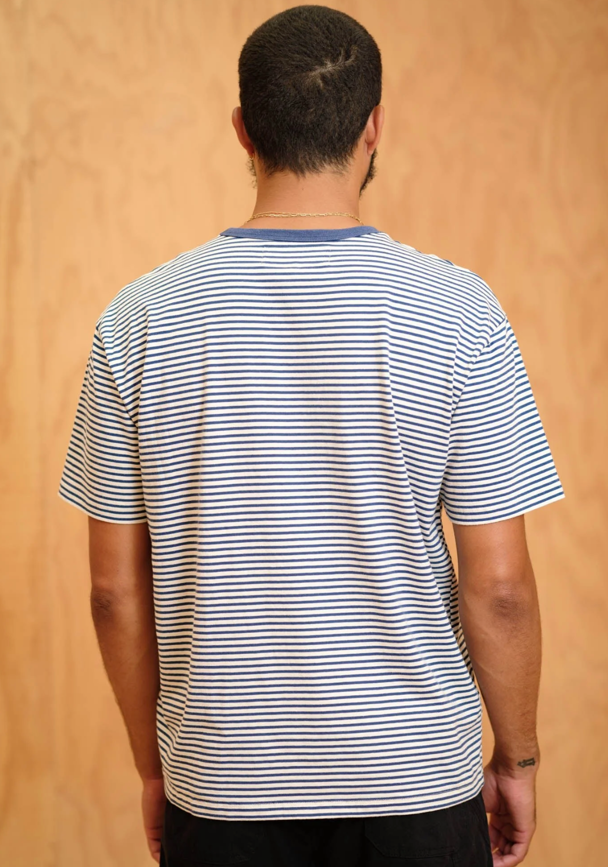 Person wearing a striped t-shirt against a beige background