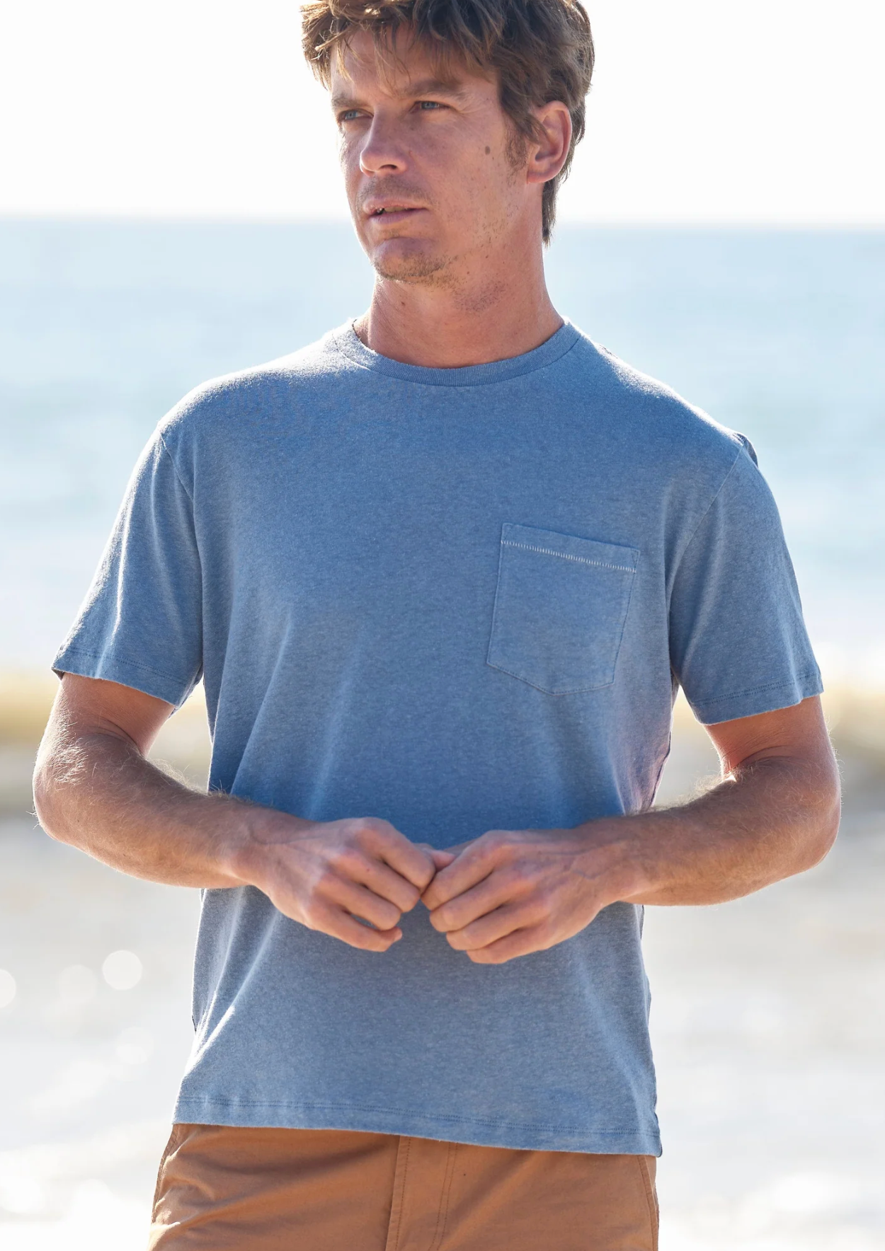 Man wearing a blue t-shirt with a pocket on a beach