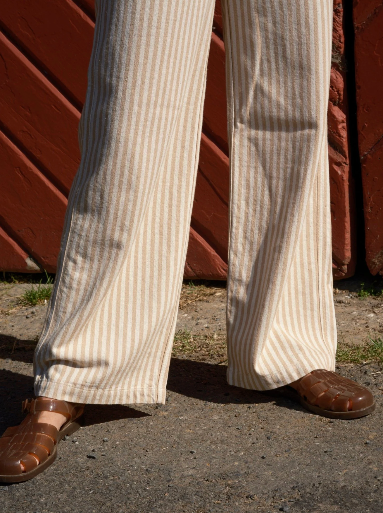 Close-up of striped pants and brown shoes against a red wooden background