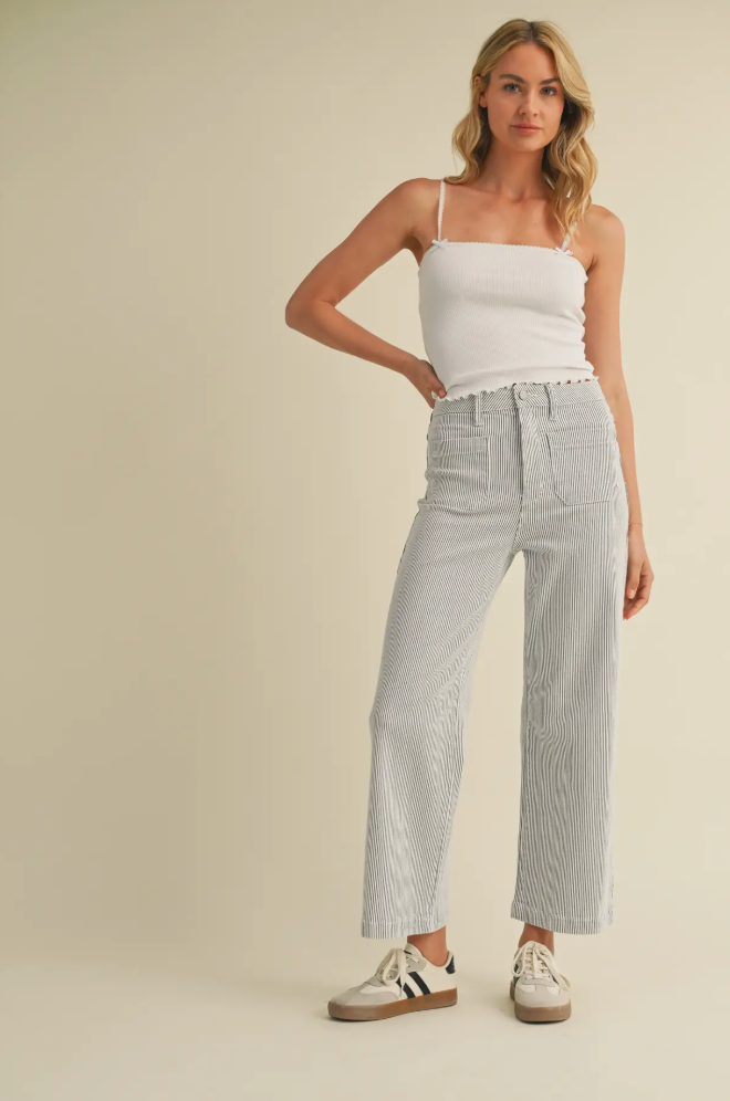 Woman wearing a white top and light gray checkered pants on a beige background