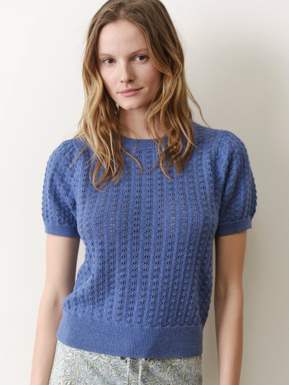 Woman wearing a blue knitted top against a plain background