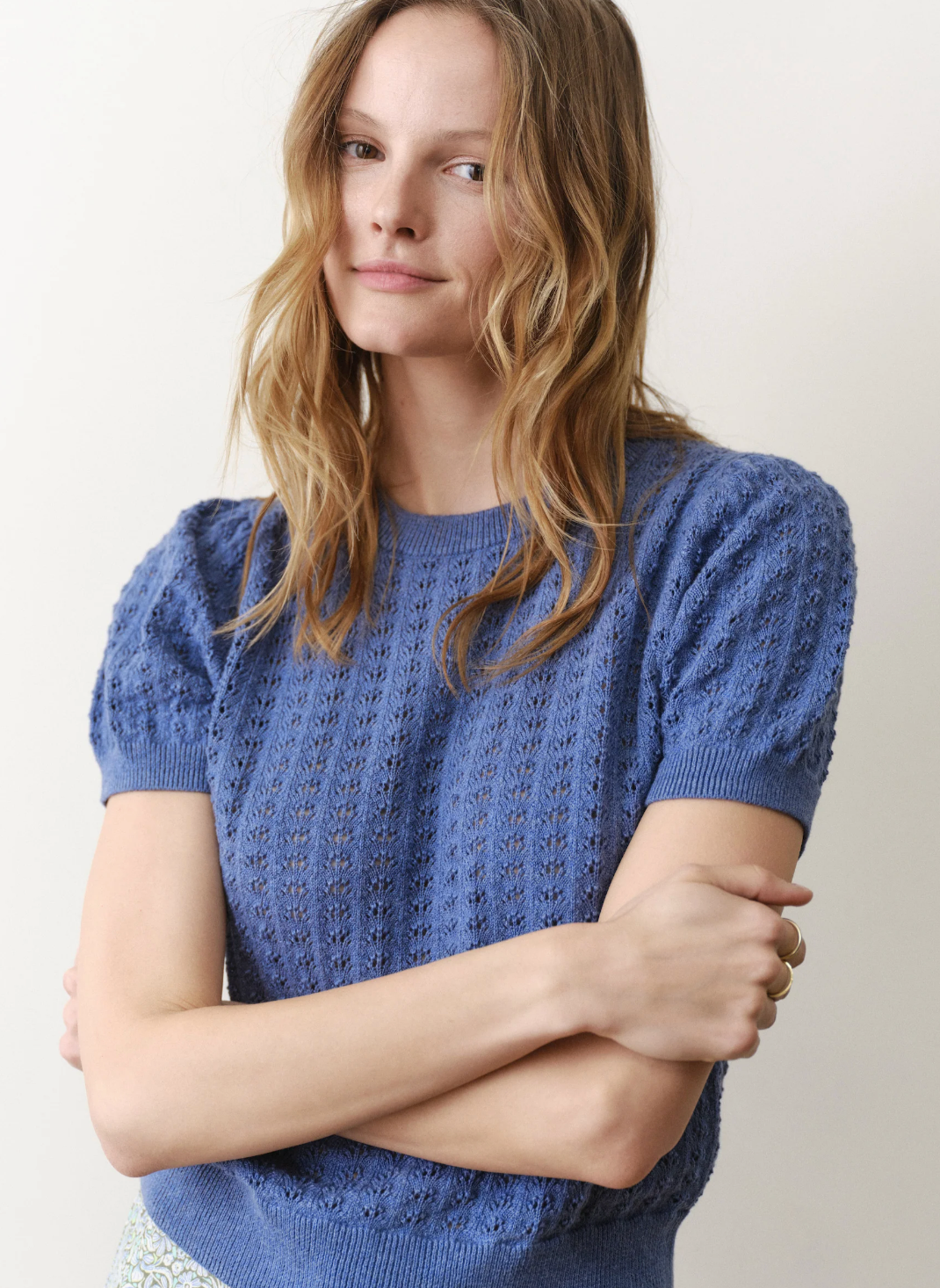 Woman wearing a blue knitted sweater against a plain background