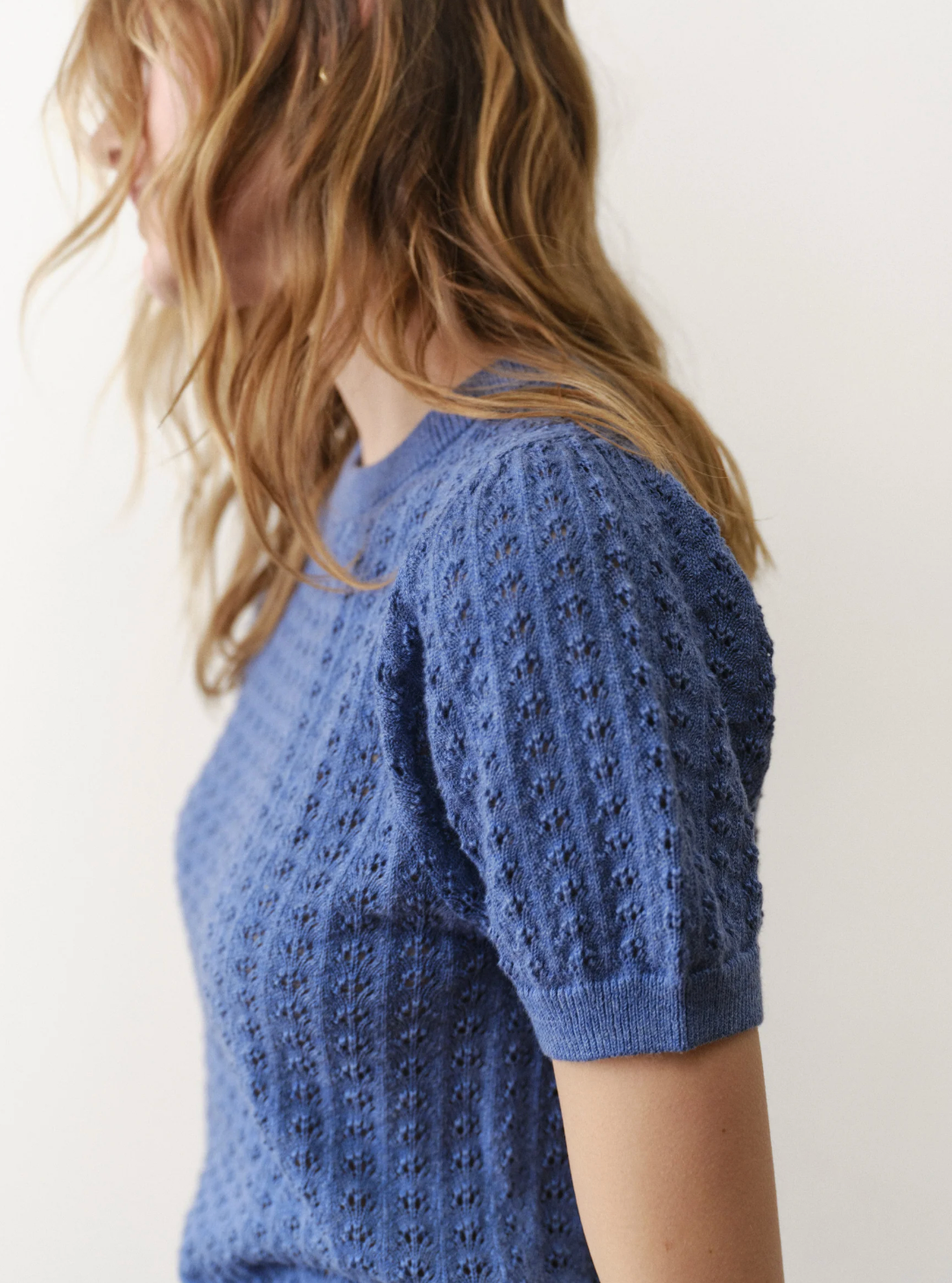 Person wearing a blue knitted sweater with a white background