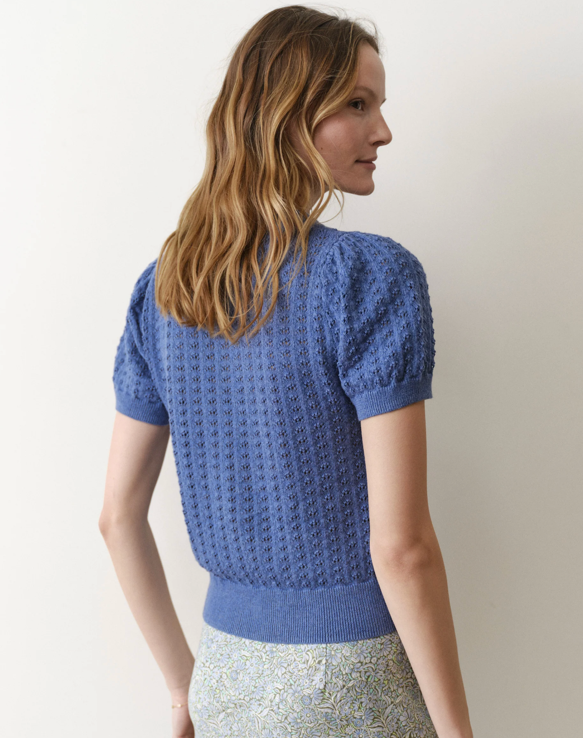 Woman wearing a blue knitted top against a plain background