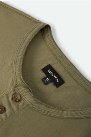 Close-up of a green shirt with a Brixton label on a white background