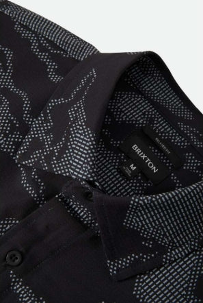 Close-up of a black patterned shirt with a brand label on a white background