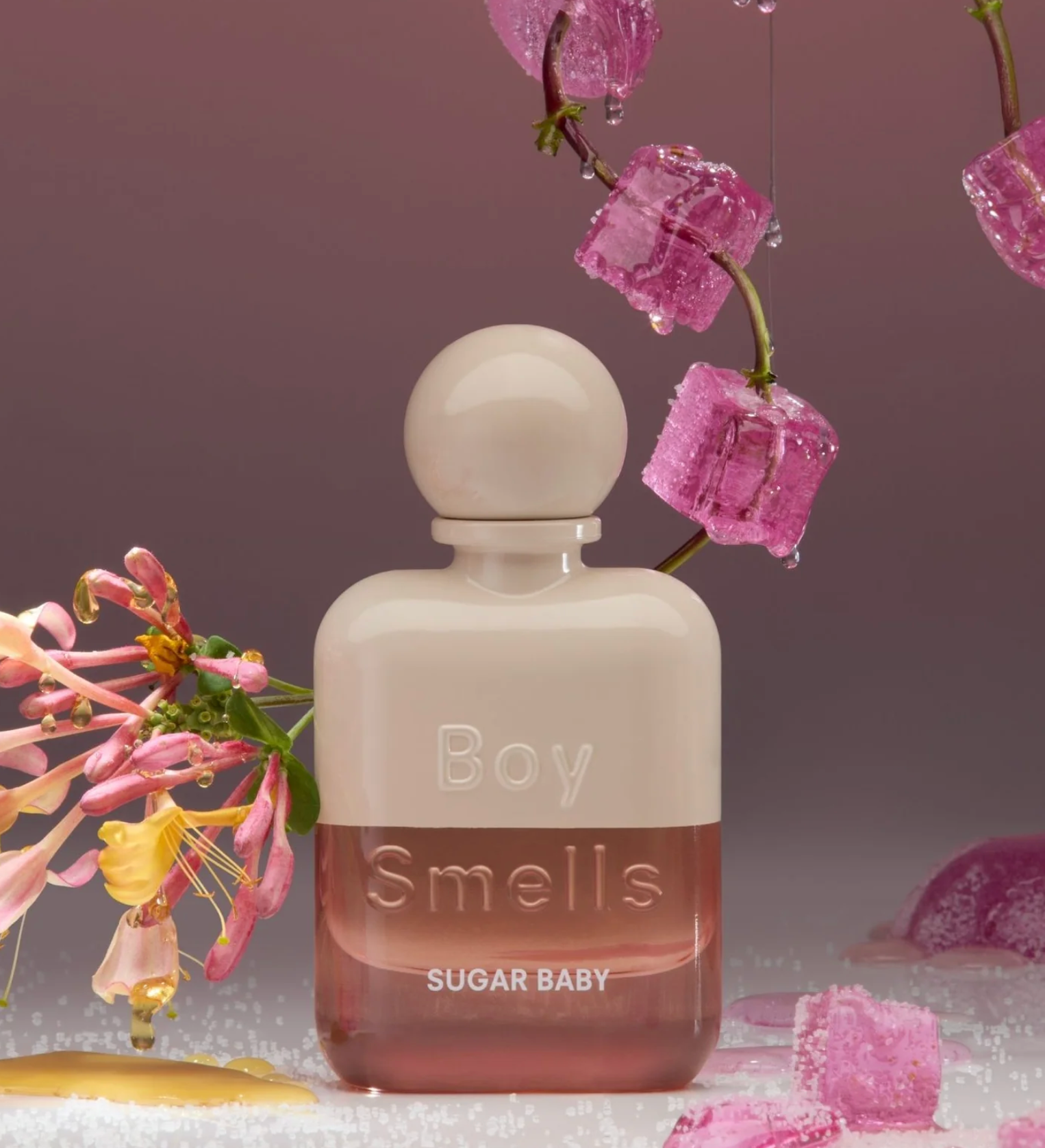 Perfume bottle labeled 'Boy Smells Sugar Baby' with floral elements on a soft purple background
