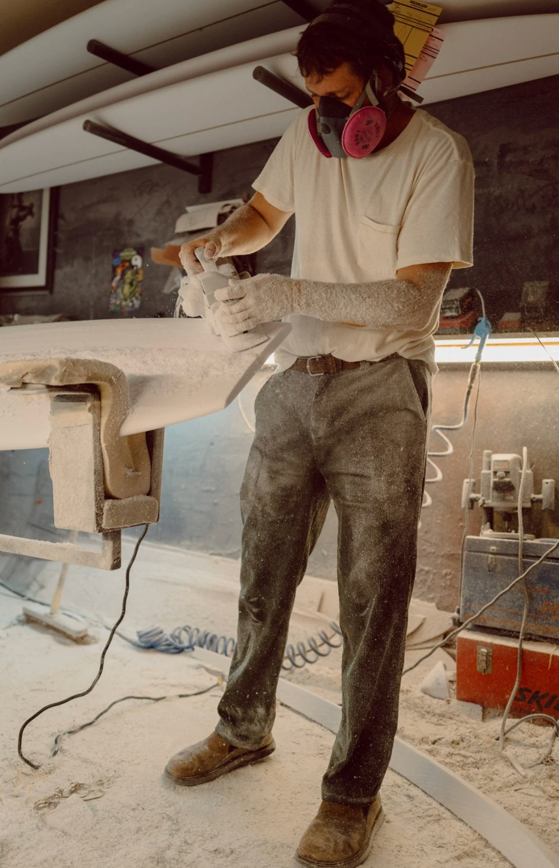 Person wearing a respirator and gloves, working with a spray gun in a workshop.