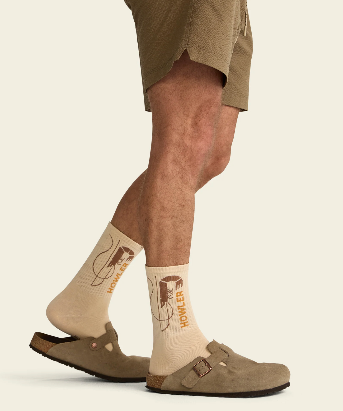 Person wearing beige socks with a logo, standing on a light background