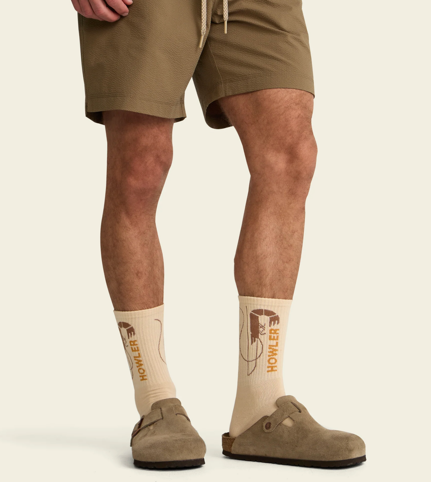 Person wearing beige socks with logo and brown shoes on a white background