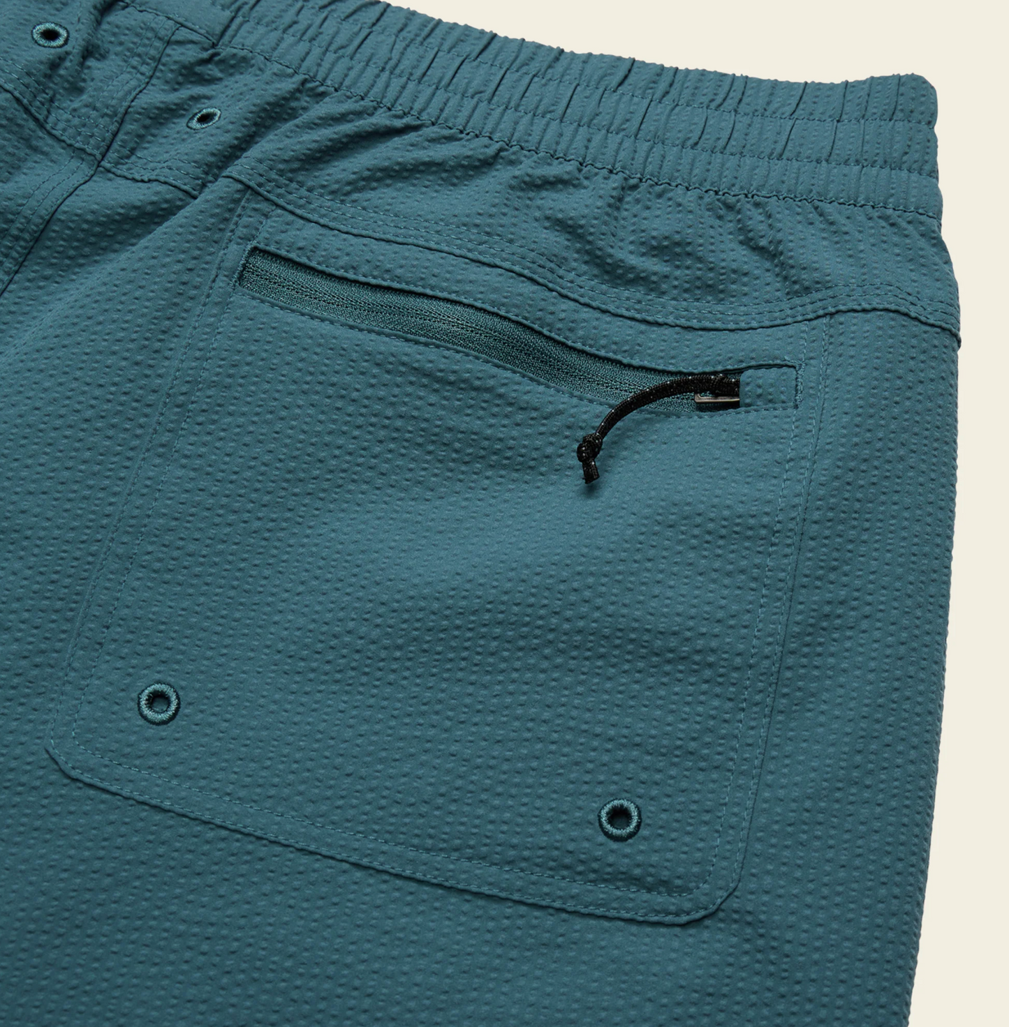 Close-up of blue textured shorts with a pocket and drawstring on a beige background