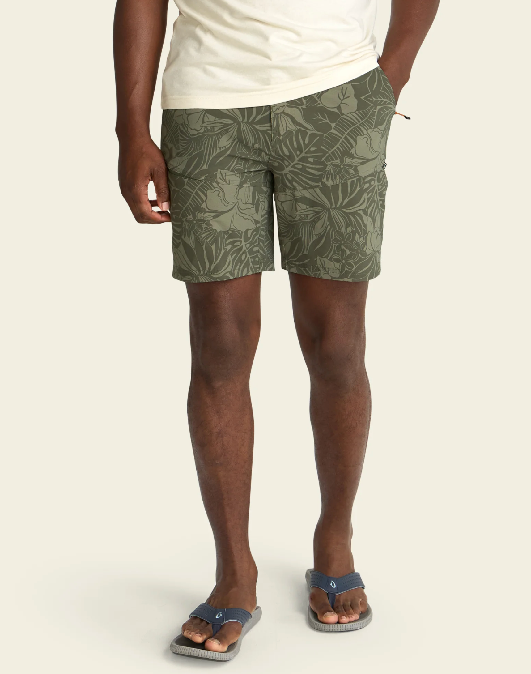 Person wearing green leaf-patterned shorts on a plain background