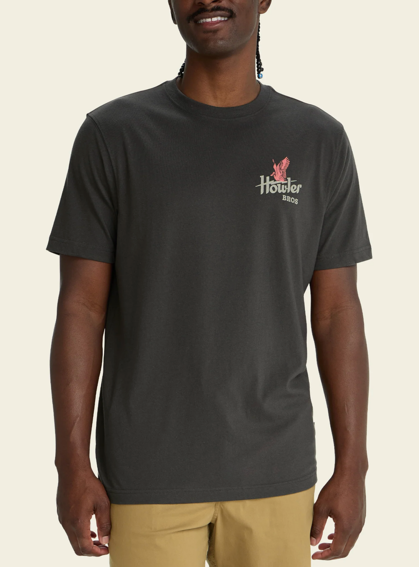 Person wearing a black t-shirt with a logo on a beige background