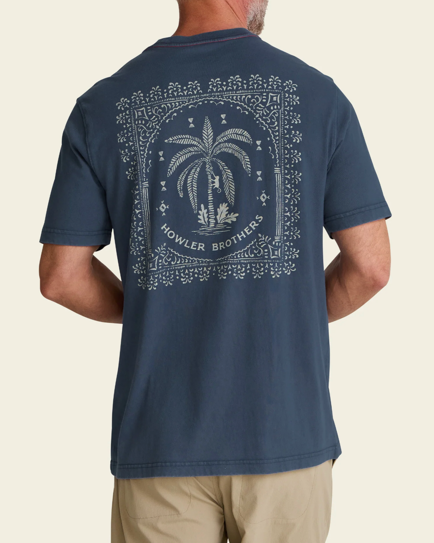 Man wearing a navy blue t-shirt with a palm tree design and 'Howler Brothers' branding on the back.