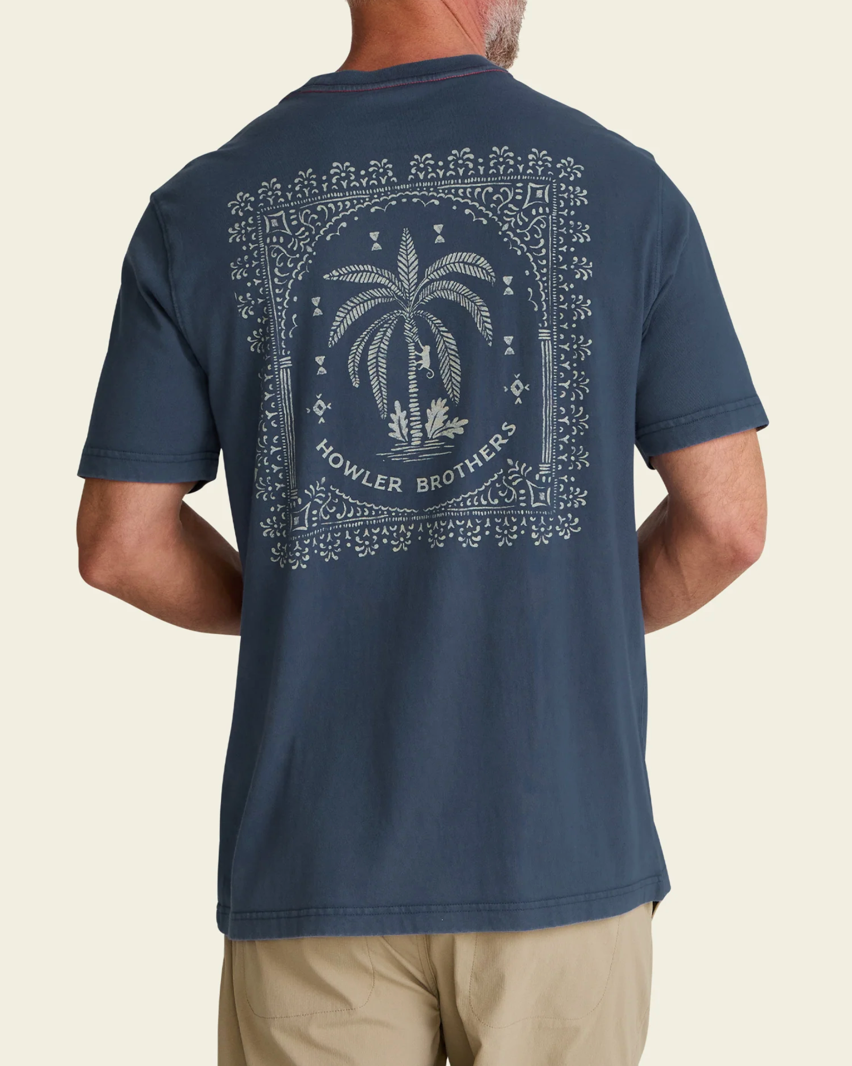 Man wearing a navy blue t-shirt with a palm tree design and 'Howler Brothers' branding on the back.