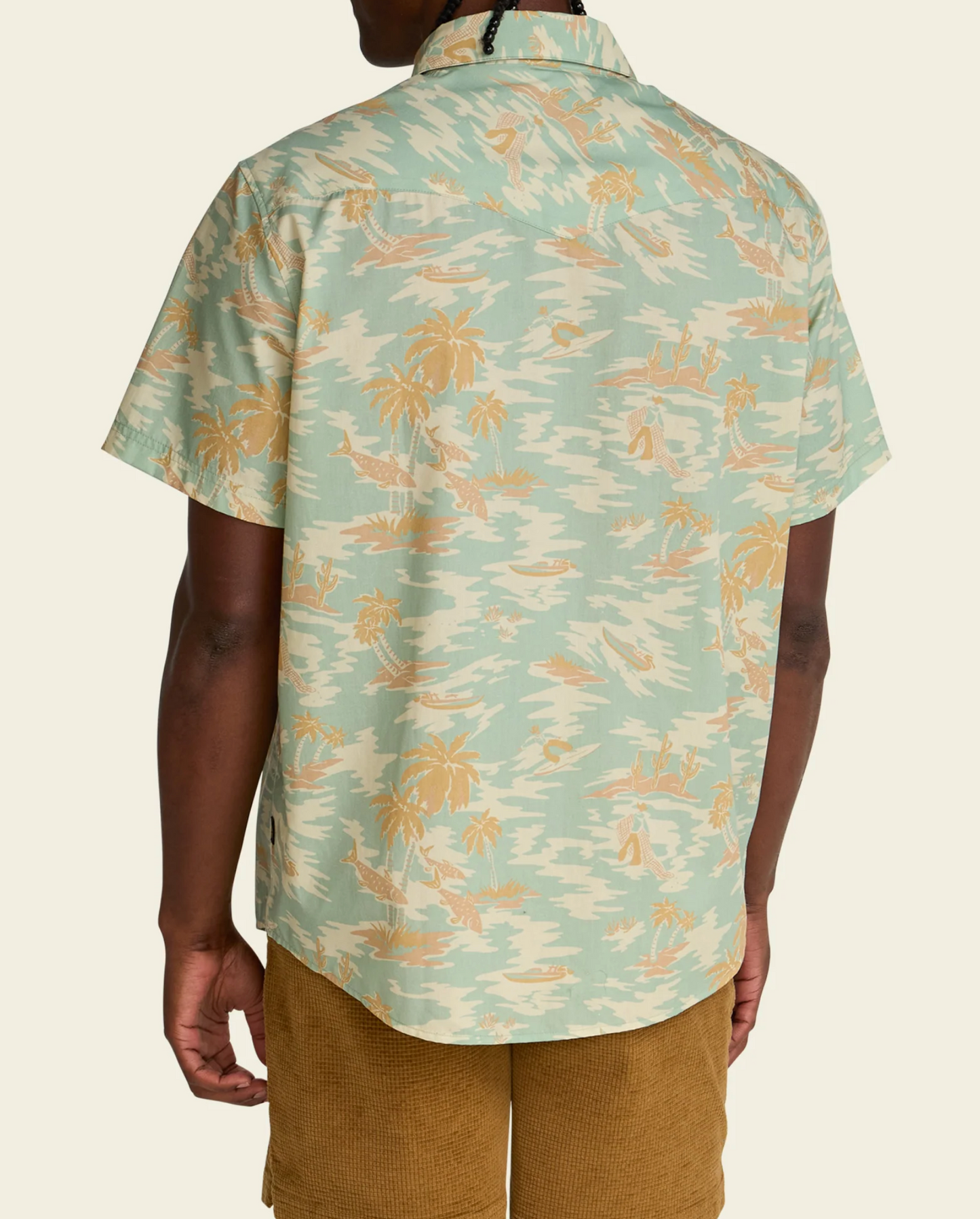 Person wearing a short-sleeve shirt with a tropical pattern on a beige background