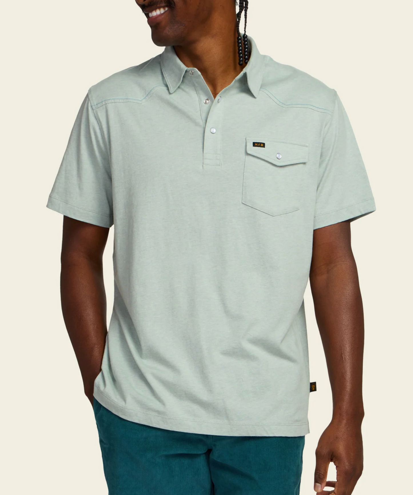 Man wearing a light gray polo shirt with a brand logo on a beige background