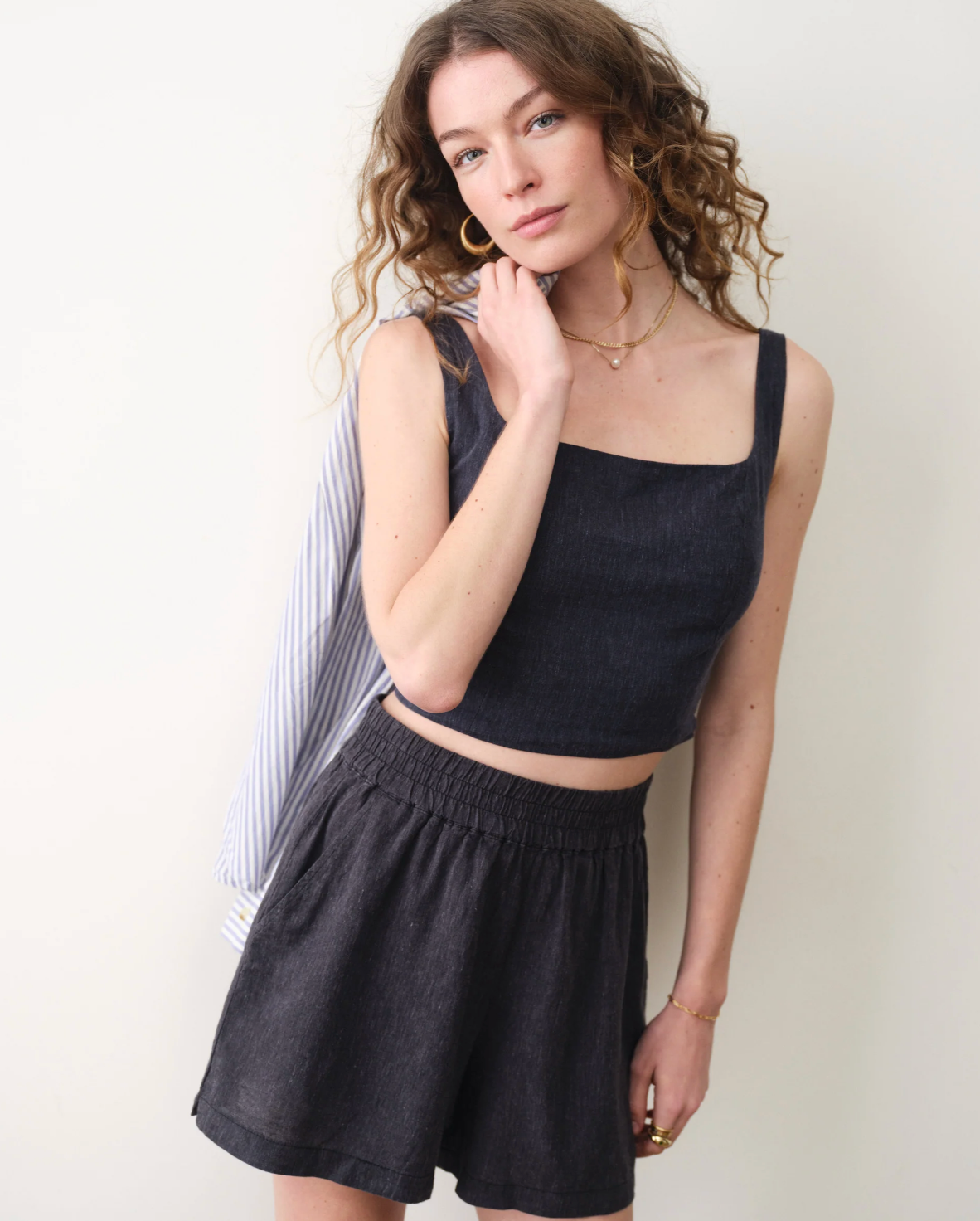 Woman wearing a black sleeveless top and shorts against a white background