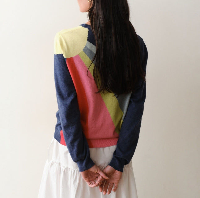 Person wearing a colorful sweater with a neutral background