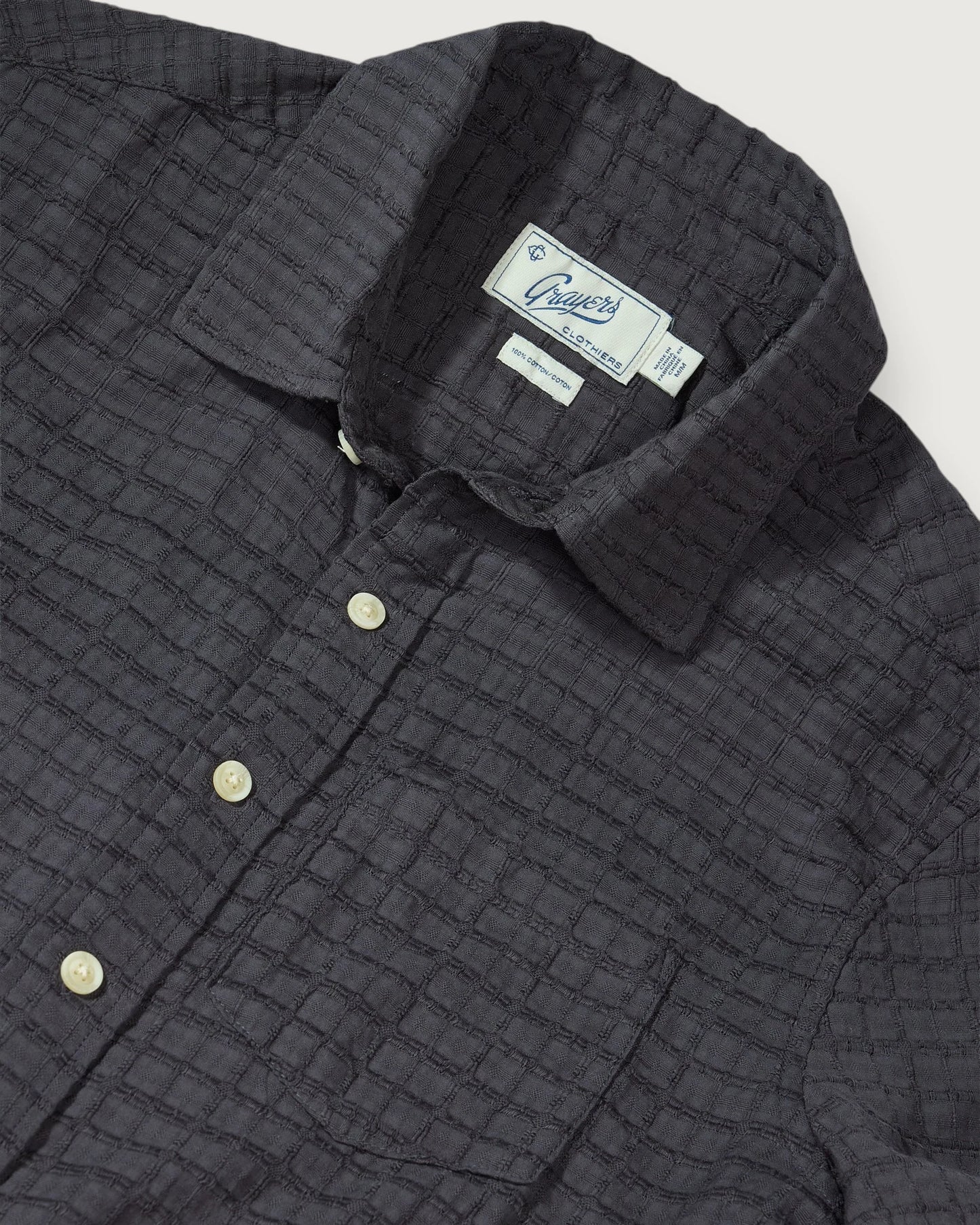 Dark quilted jacket with brand label on a light gray background
