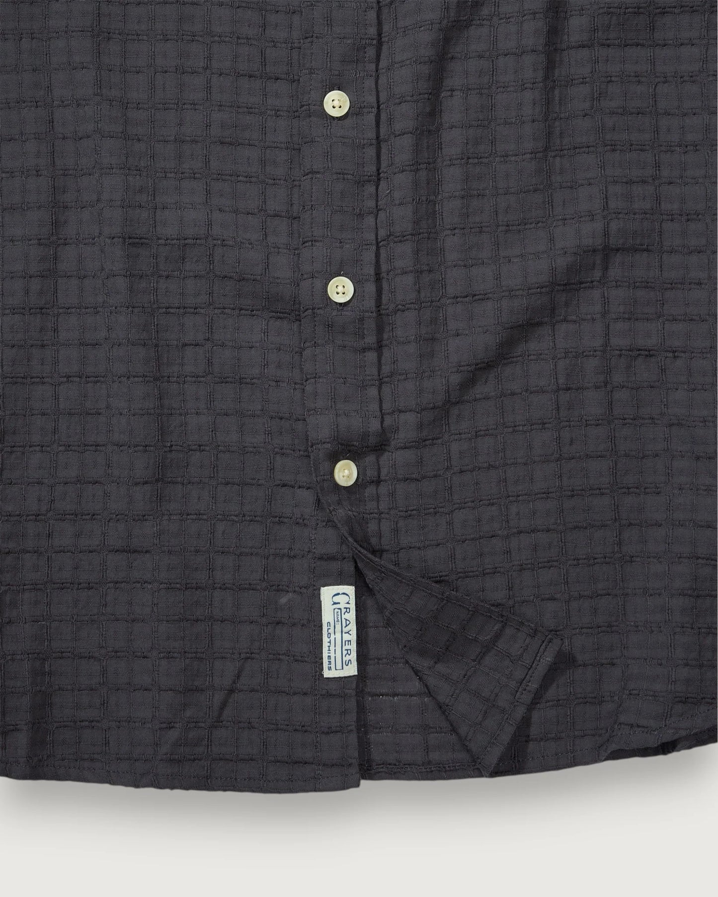 Close-up of a dark gray textured shirt with buttons on a white background