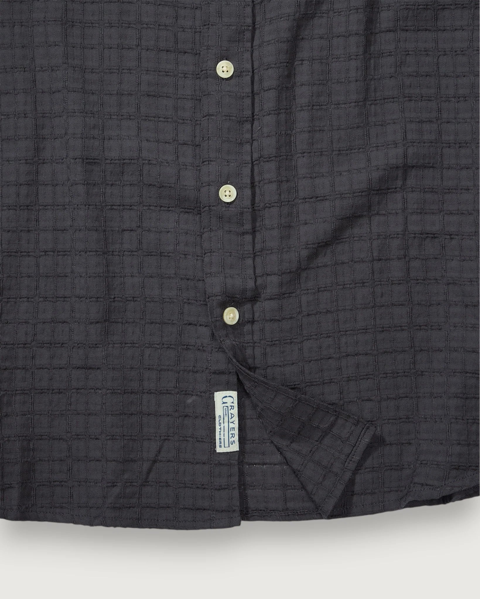 Close-up of a dark gray textured shirt with buttons on a white background