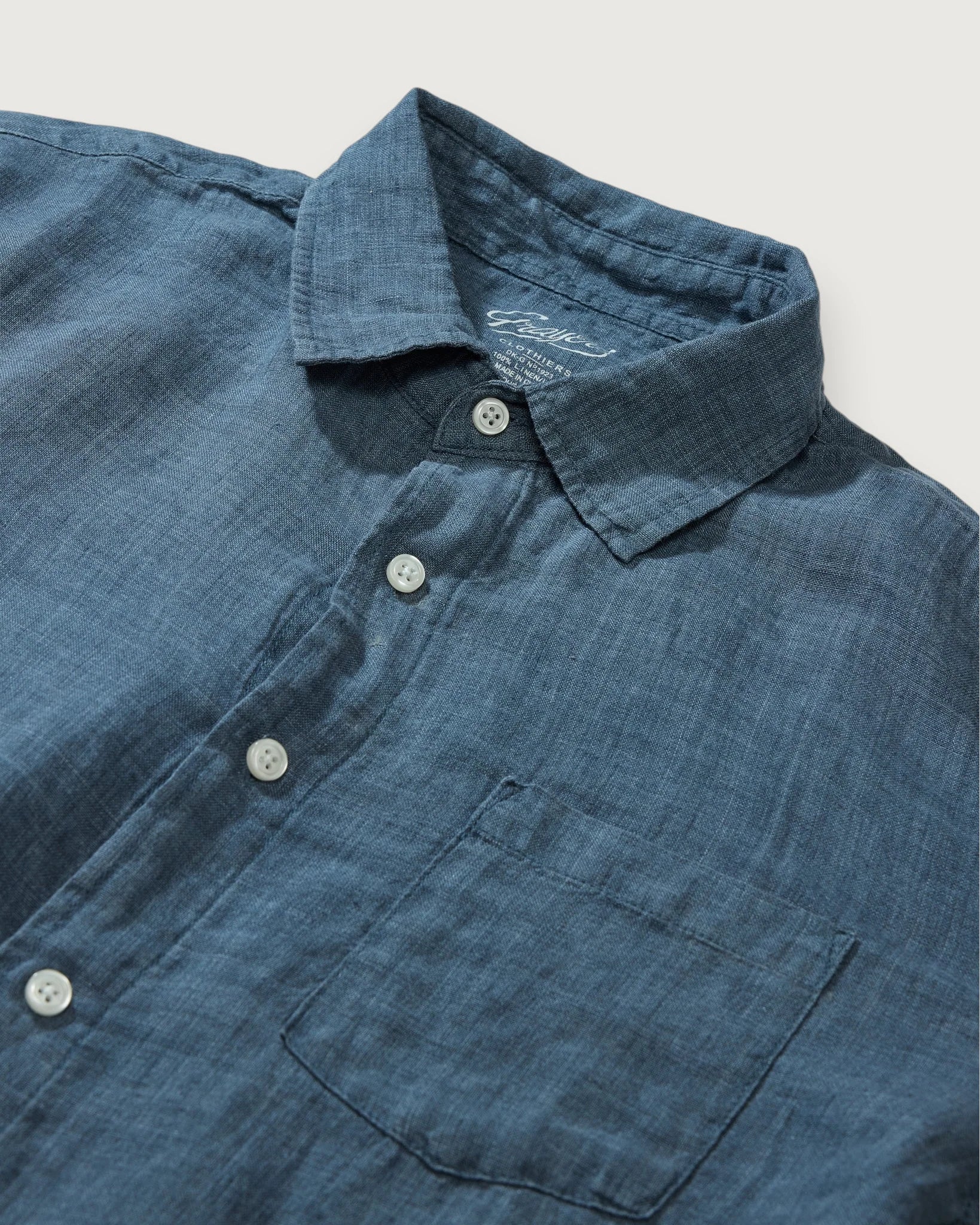 Close-up of a blue denim shirt with collar and buttons on a light gray background