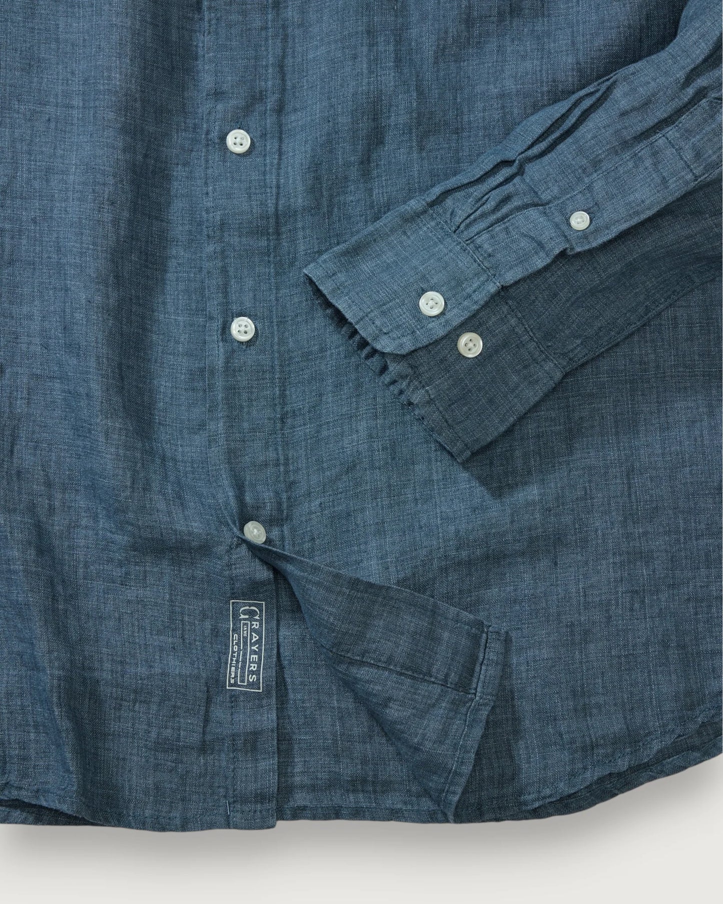Close-up of a blue denim shirt with a brand label on a white background