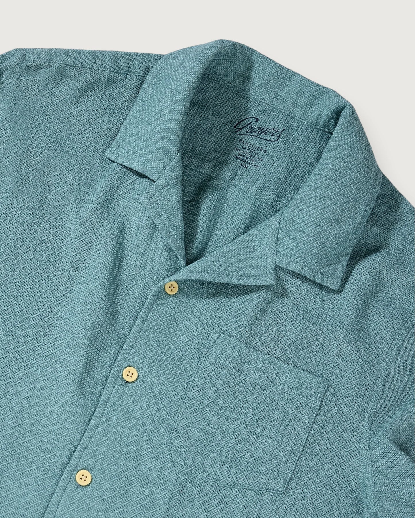 Teal shirt with collar and buttons on a light gray background