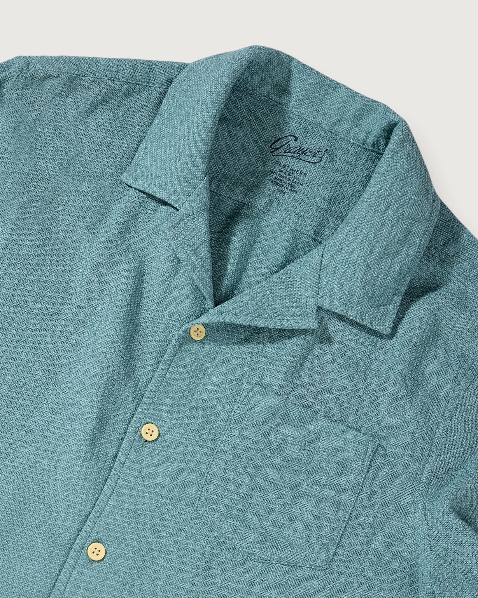 Teal shirt with collar and buttons on a light gray background