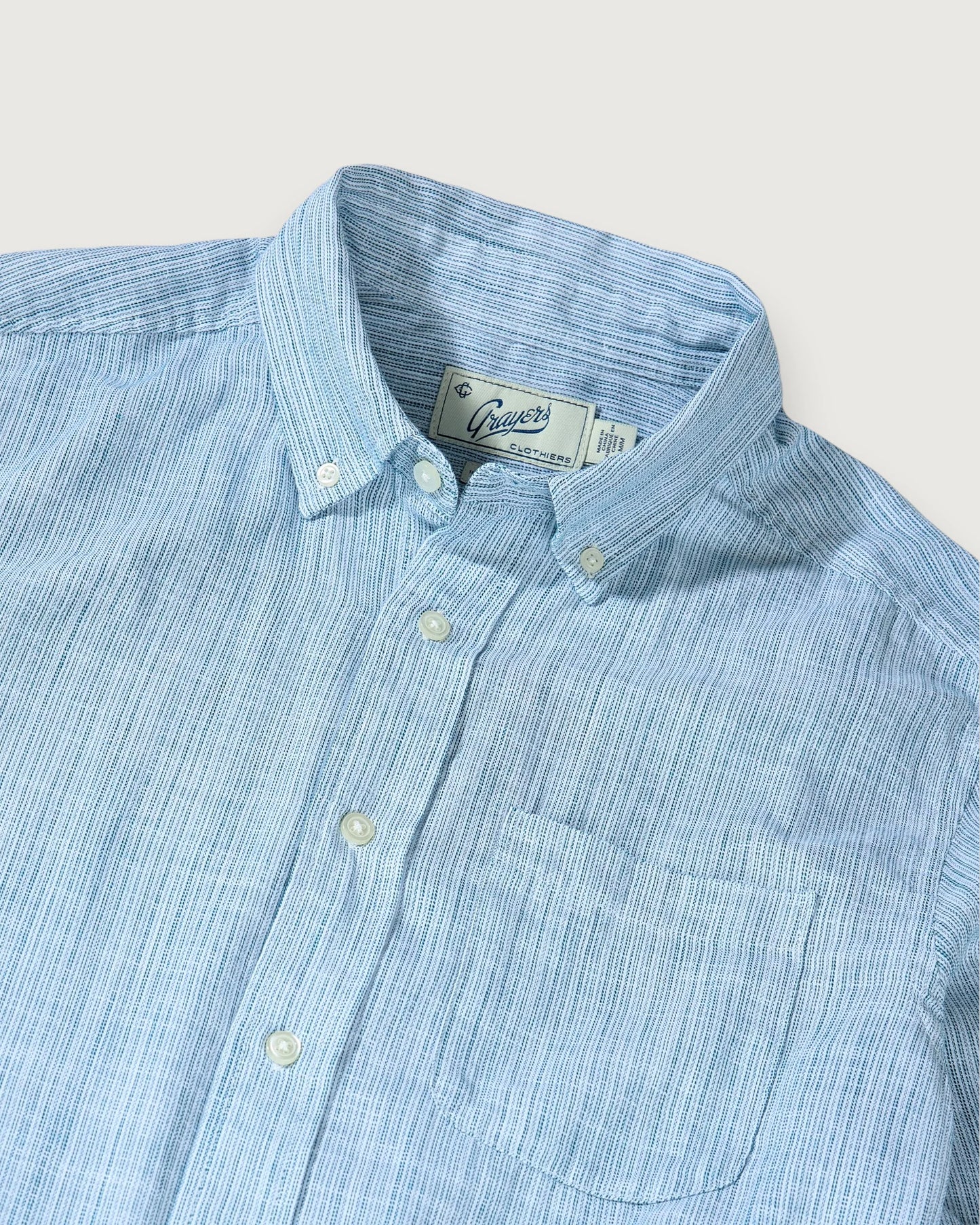 Light blue striped shirt with a collar and buttons on a light gray background
