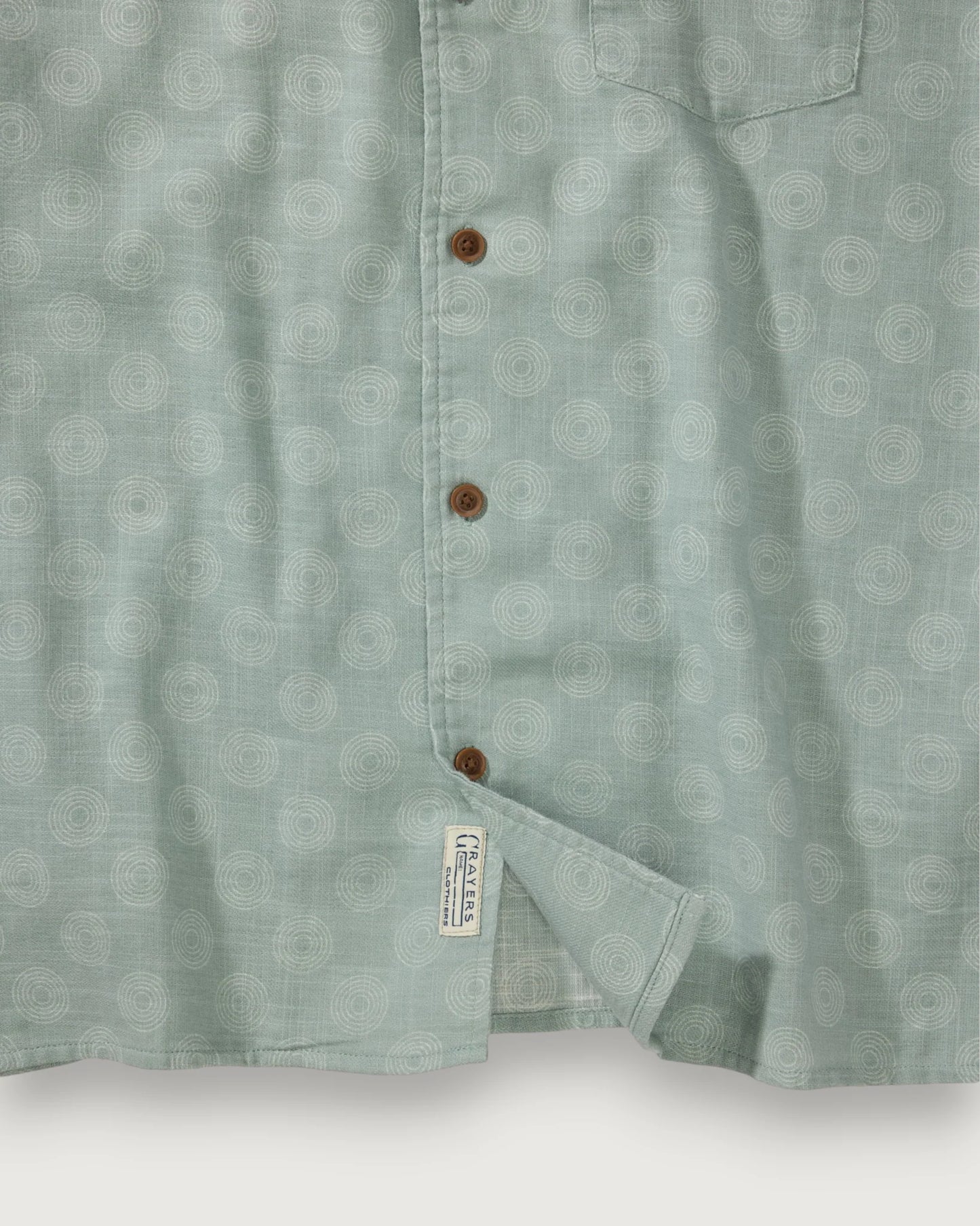Close-up of a light green patterned shirt with buttons on a white background