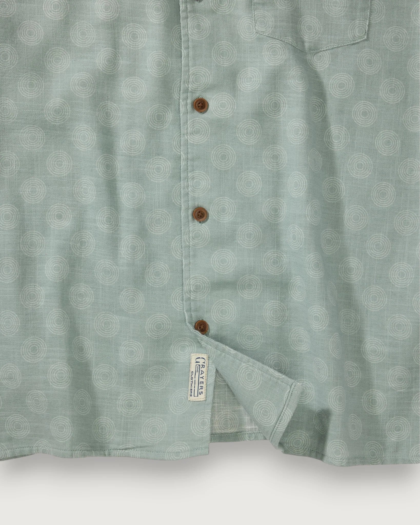 Close-up of a light green patterned shirt with buttons on a white background