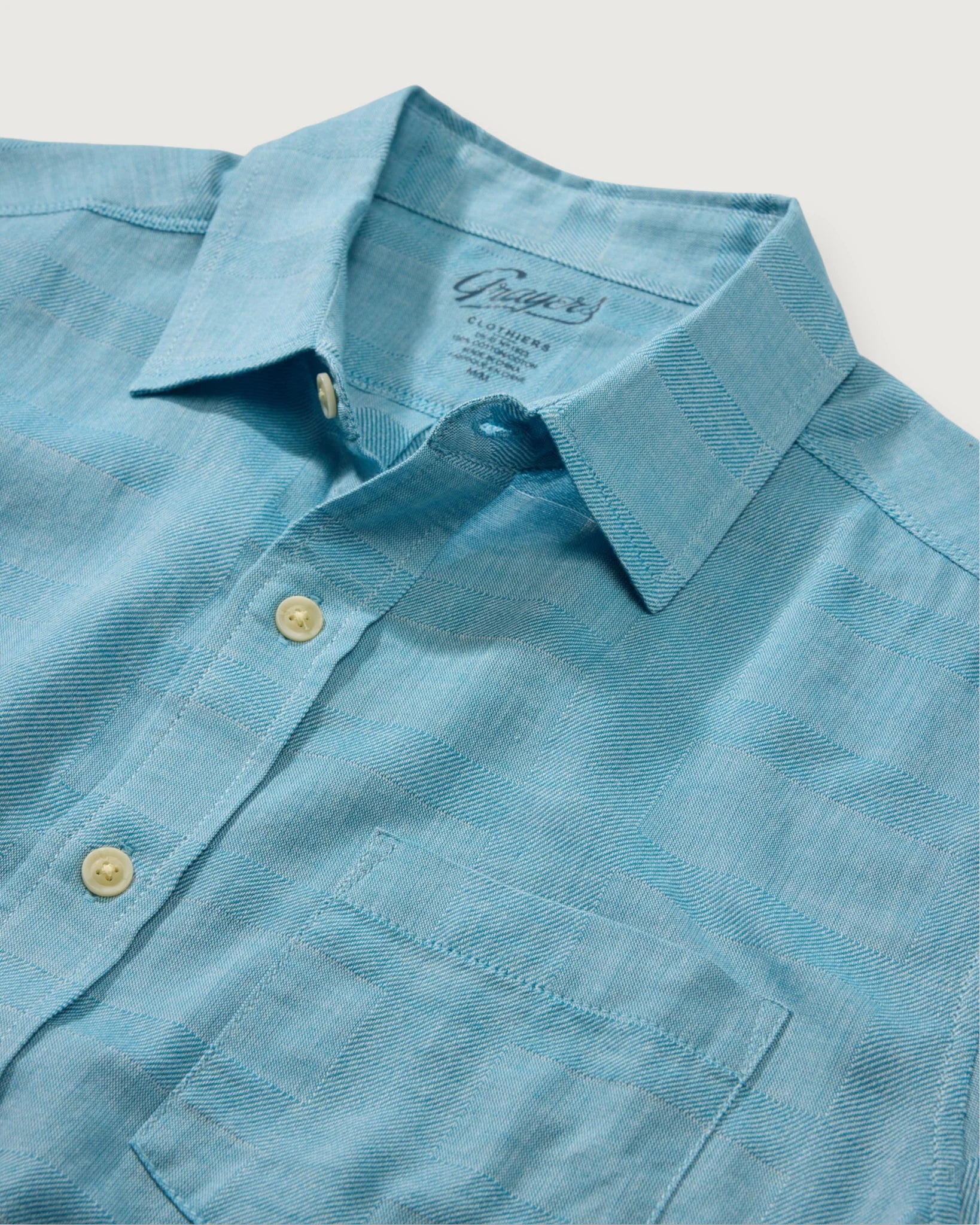Blue shirt with collar and buttons on a light gray background