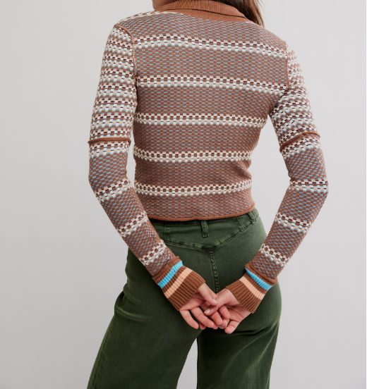 A person shown from the back wearing a fitted knit sweater with horizontal geometric patterns in brown, cream, and muted blue, paired with dark green pants, against a plain light gray studio background.