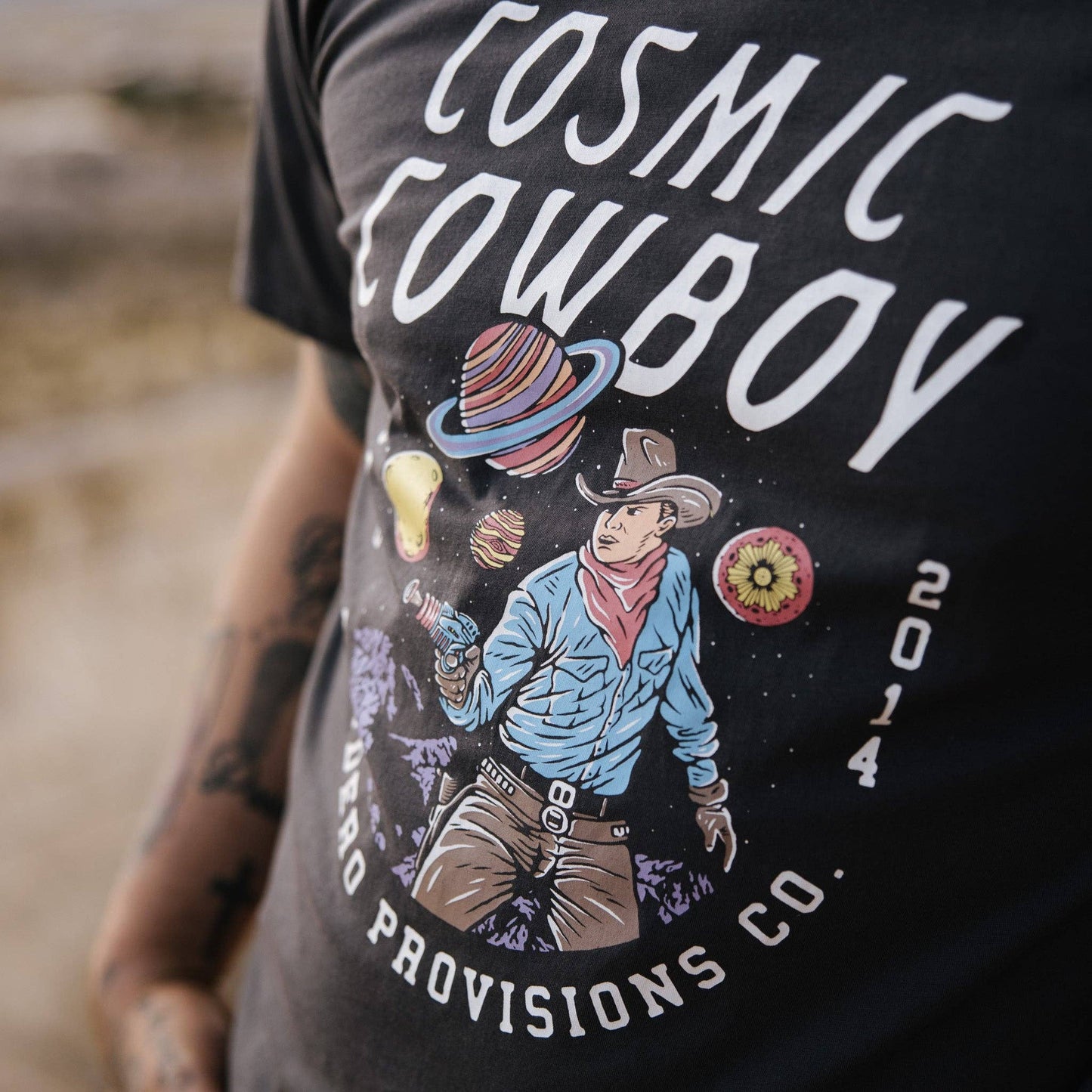 T-shirt with 'Cosmic Cowboy' design and text on a blurred background
