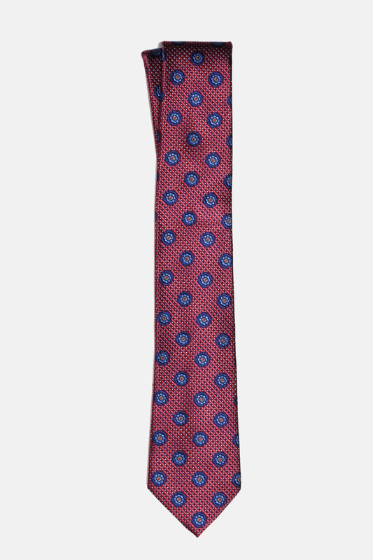 A classic necktie with a red base, featuring a repeating pattern of blue and white circular medallions, displayed flat against a light gray background.