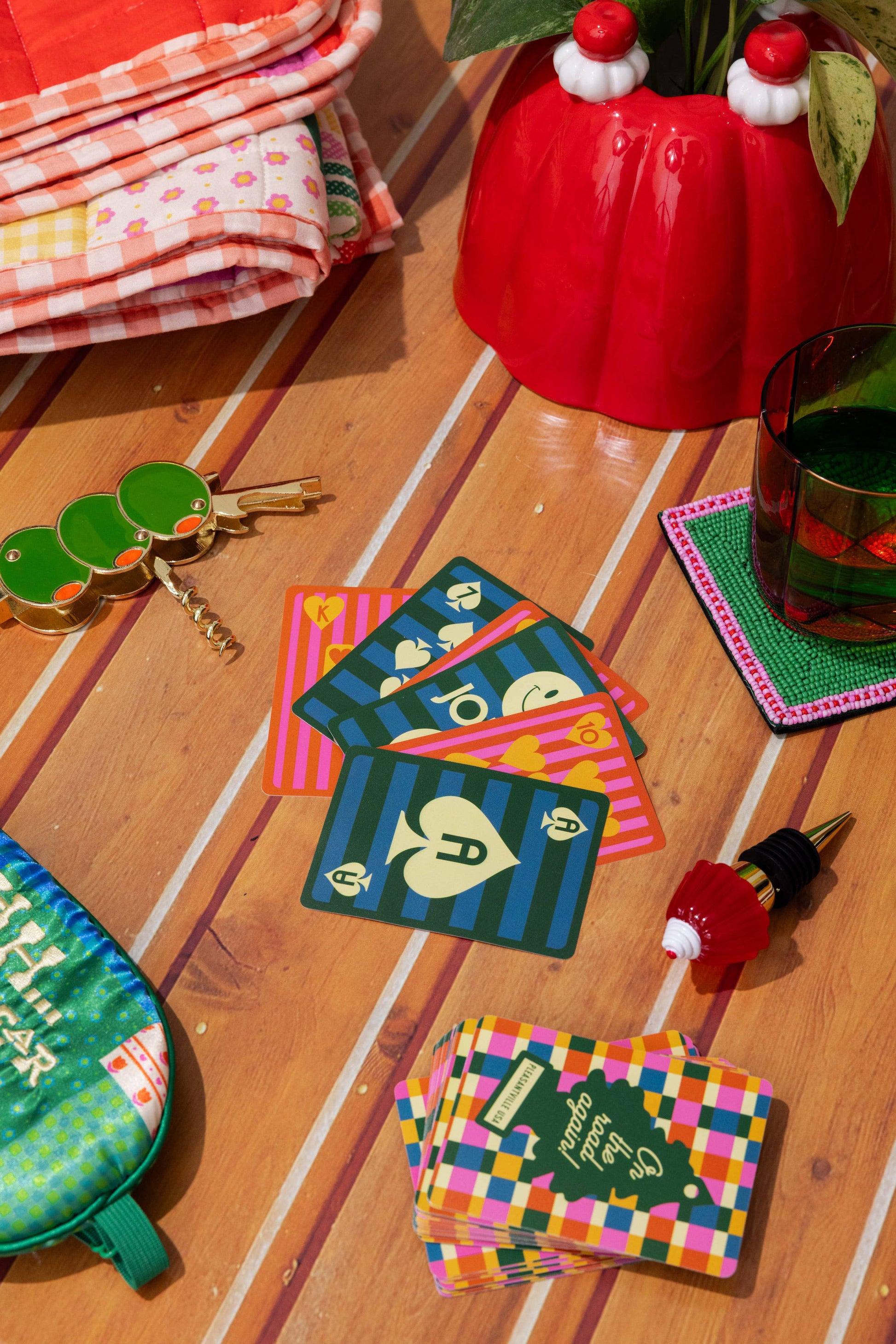 Colorful coasters on a wooden floor with a red vase and keys in the background.