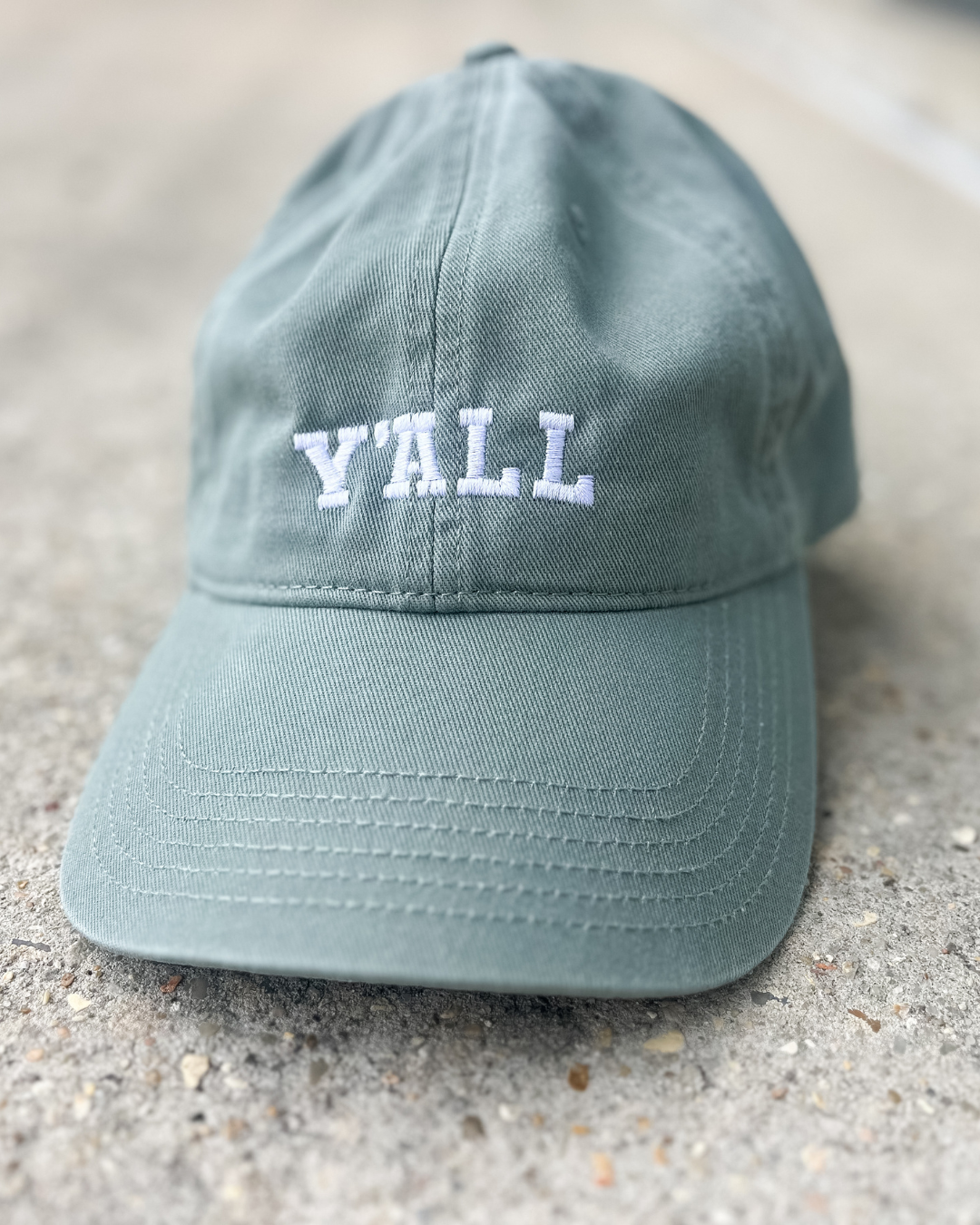Light blue cap with 'Y'ALL' text on a concrete surface
