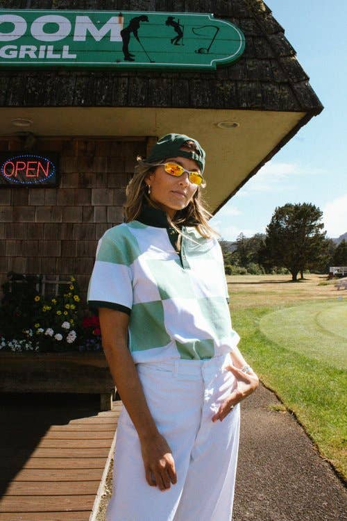Woman in a golf outfit standing on a golf course with a restaurant in the background
