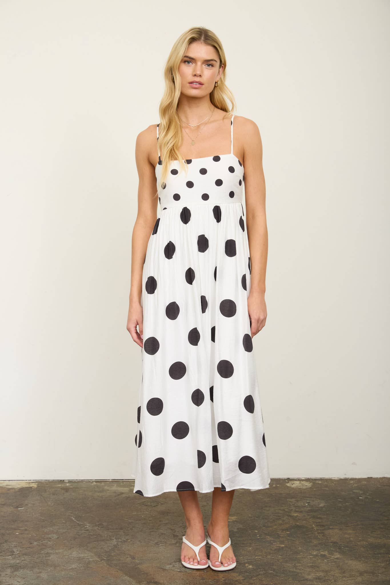 Woman wearing a white dress with black polka dots against a plain background
