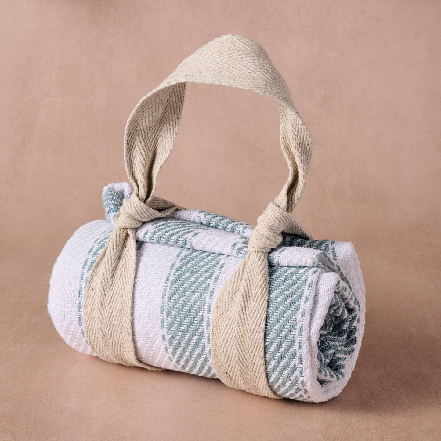 Rolled-up towel with a rope handle on a beige background
