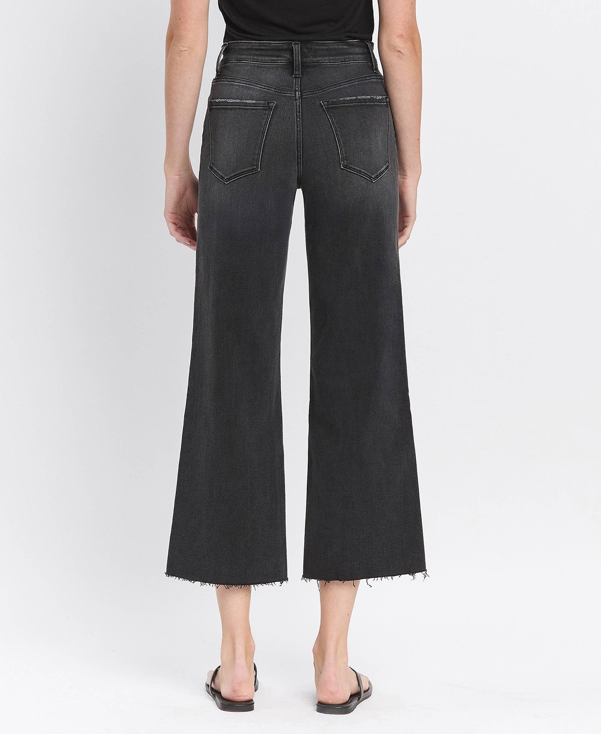 Person wearing black wide-leg jeans on a white background